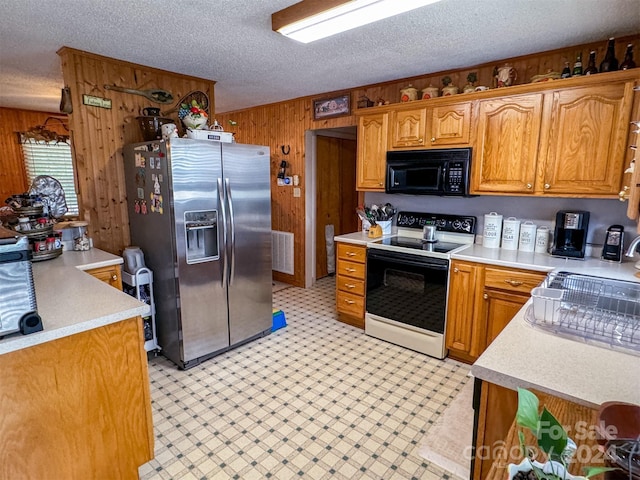 kitchen with electric range, stainless steel fridge with ice dispenser, wood walls, and a textured ceiling