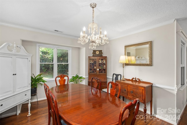 dining space featuring a textured ceiling, dark hardwood / wood-style flooring, ornamental molding, and an inviting chandelier