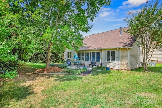 rear view of house featuring central AC unit, a patio area, and a yard