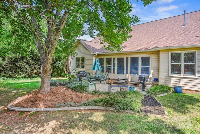 rear view of property with a sunroom, a lawn, and a patio