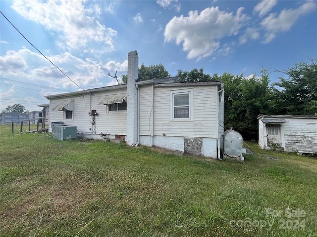 back of house with a yard and central air condition unit