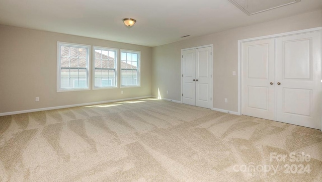 unfurnished bedroom with multiple closets and light carpet