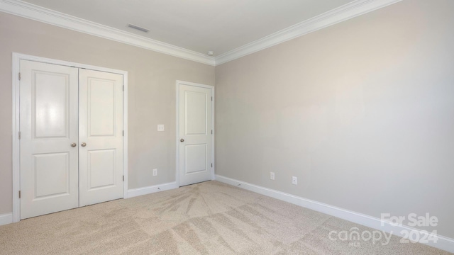 unfurnished bedroom with a closet, light colored carpet, and crown molding