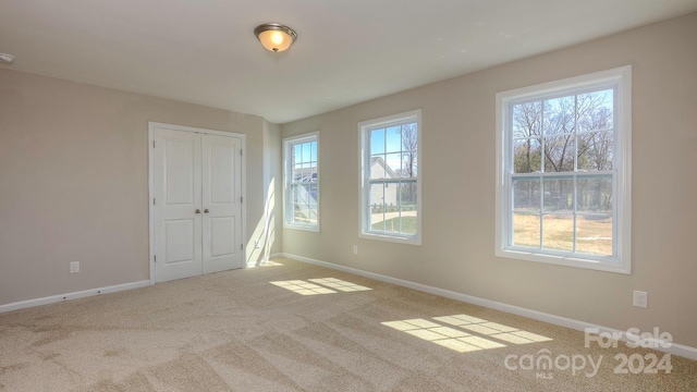 unfurnished bedroom with a closet, multiple windows, and carpet