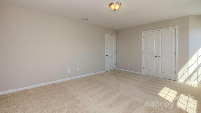 unfurnished bedroom featuring light colored carpet and a closet