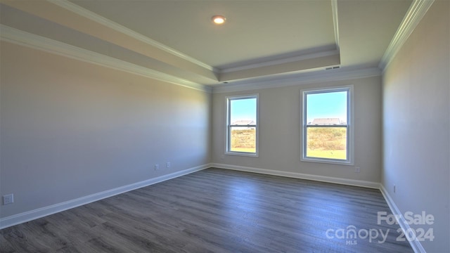 unfurnished room featuring crown molding, a tray ceiling, dark wood finished floors, and baseboards