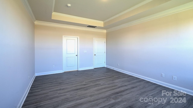 unfurnished bedroom with visible vents, a raised ceiling, baseboards, dark wood-style floors, and ornamental molding