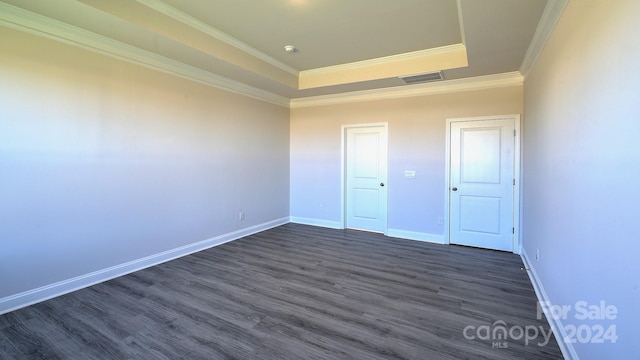 unfurnished bedroom with dark wood-style flooring, visible vents, baseboards, a tray ceiling, and crown molding