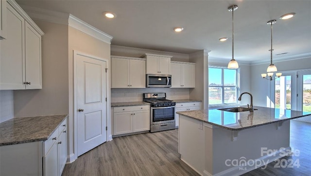 kitchen with ornamental molding, appliances with stainless steel finishes, a sink, and white cabinetry