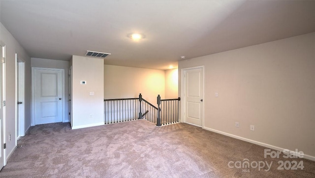 unfurnished room with carpet floors, visible vents, and baseboards