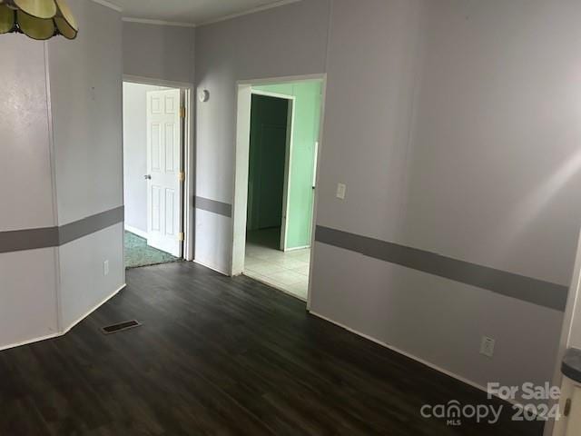 empty room featuring crown molding and dark hardwood / wood-style floors