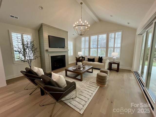 living room featuring light hardwood / wood-style flooring, vaulted ceiling with beams, a notable chandelier, and a fireplace