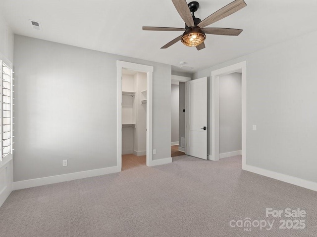 unfurnished bedroom with ceiling fan, a spacious closet, and light colored carpet