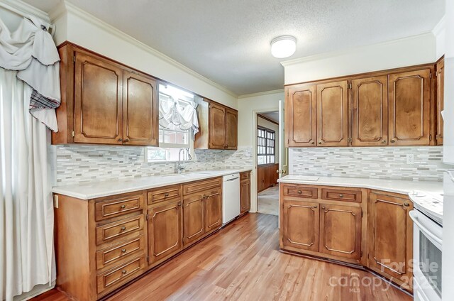 kitchen with sink, crown molding, white appliances, backsplash, and light hardwood / wood-style floors