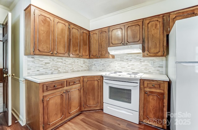 kitchen with crown molding, backsplash, white appliances, and hardwood / wood-style flooring