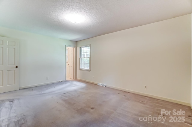 empty room with light colored carpet and a textured ceiling