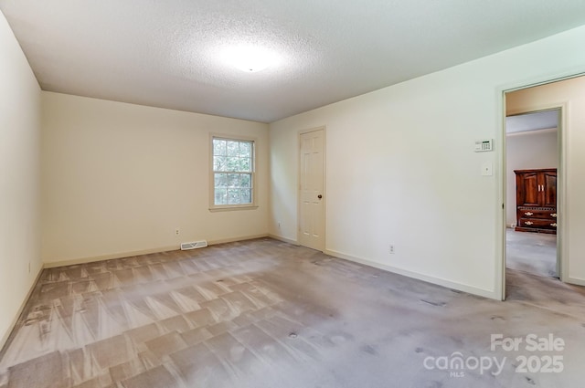 carpeted empty room featuring a textured ceiling