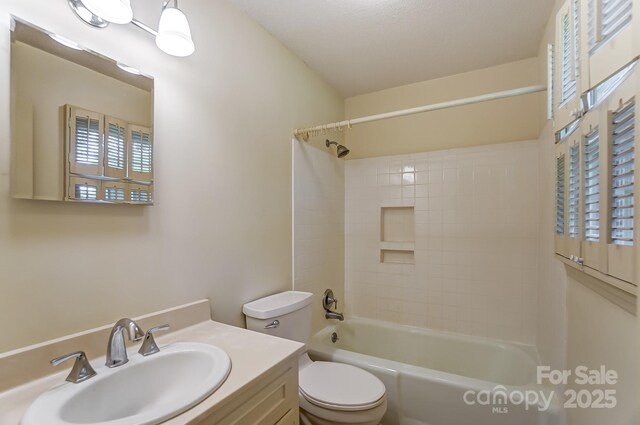 full bathroom with vanity, tiled shower / bath combo, and toilet