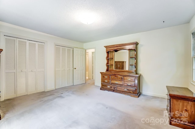 carpeted bedroom with two closets and a textured ceiling