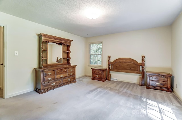 bedroom featuring light colored carpet and a textured ceiling