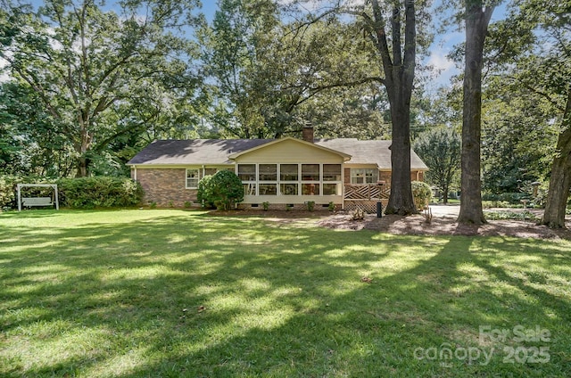 rear view of house featuring a sunroom and a yard