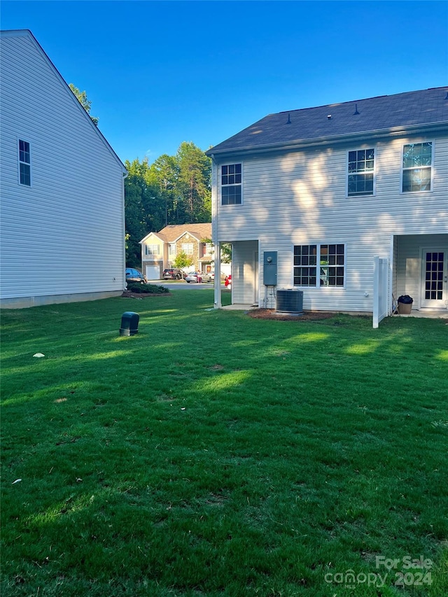 back of house with a yard and central air condition unit