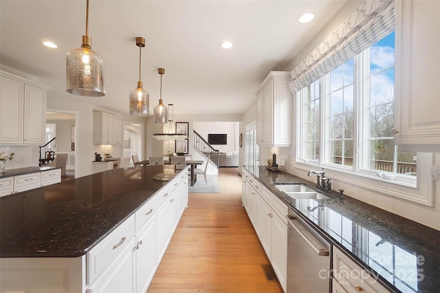 kitchen with sink, white cabinetry, hanging light fixtures, dishwasher, and dark stone counters