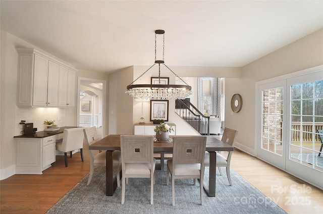 dining space with light hardwood / wood-style floors and a notable chandelier