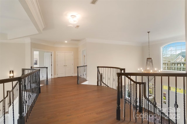 hallway with dark wood-type flooring, ornamental molding, and a notable chandelier