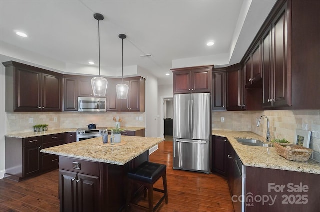 kitchen with a kitchen island, appliances with stainless steel finishes, sink, dark hardwood / wood-style flooring, and hanging light fixtures