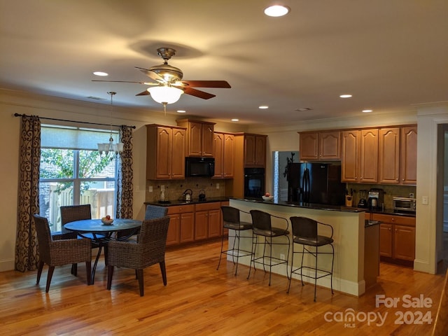 kitchen with backsplash, light hardwood / wood-style floors, black appliances, and ceiling fan