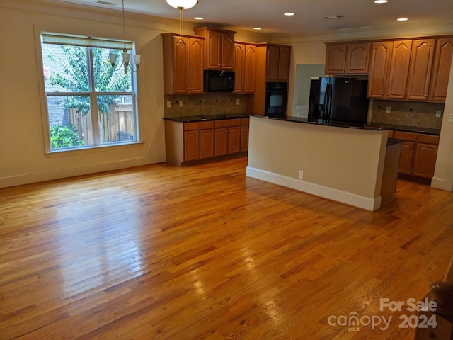 kitchen with backsplash, light wood-type flooring, black appliances, and a wealth of natural light