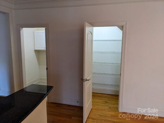 hall with ornamental molding and light hardwood / wood-style floors