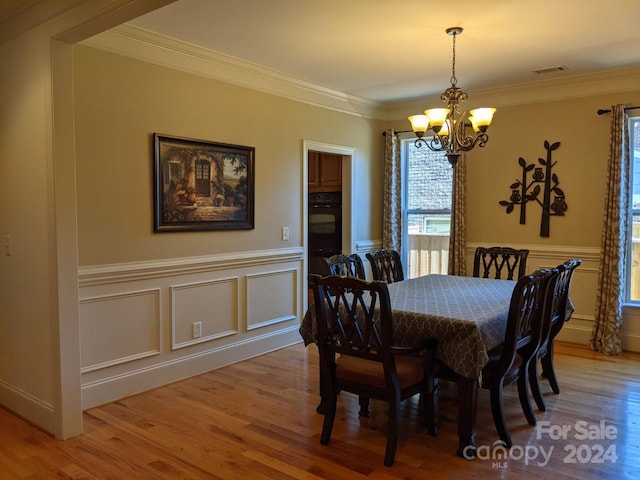 dining area featuring crown molding, wood-type flooring, and a notable chandelier