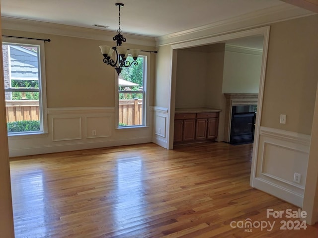 unfurnished dining area with plenty of natural light, a chandelier, and light hardwood / wood-style flooring