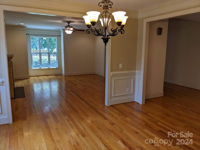 unfurnished dining area with ornamental molding, ceiling fan with notable chandelier, and light wood-type flooring