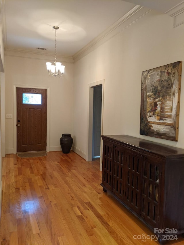 entrance foyer with crown molding, wood-type flooring, and an inviting chandelier