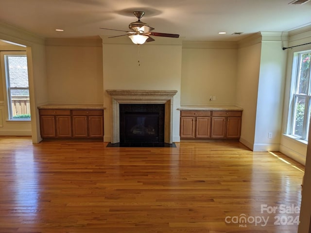 unfurnished living room featuring ornamental molding, plenty of natural light, ceiling fan, and light hardwood / wood-style flooring