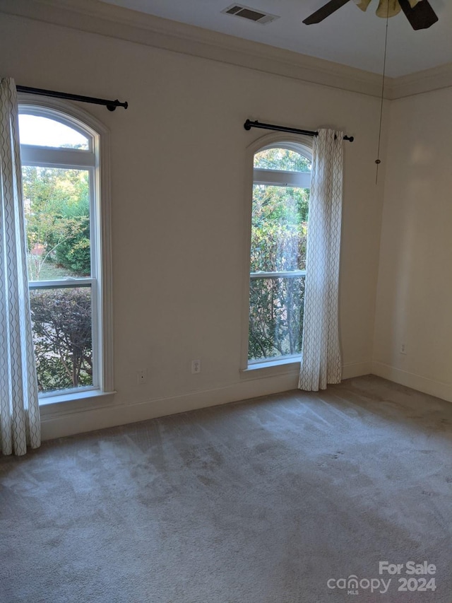 empty room with ornamental molding, light colored carpet, and ceiling fan