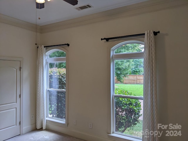 interior space featuring ceiling fan, ornamental molding, and light colored carpet