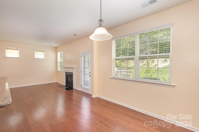 unfurnished living room featuring plenty of natural light and hardwood / wood-style floors