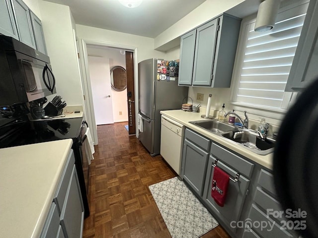 kitchen with gray cabinetry, dark parquet floors, black appliances, and sink