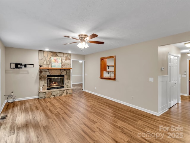 unfurnished living room with ceiling fan, wood-type flooring, a fireplace, and a textured ceiling