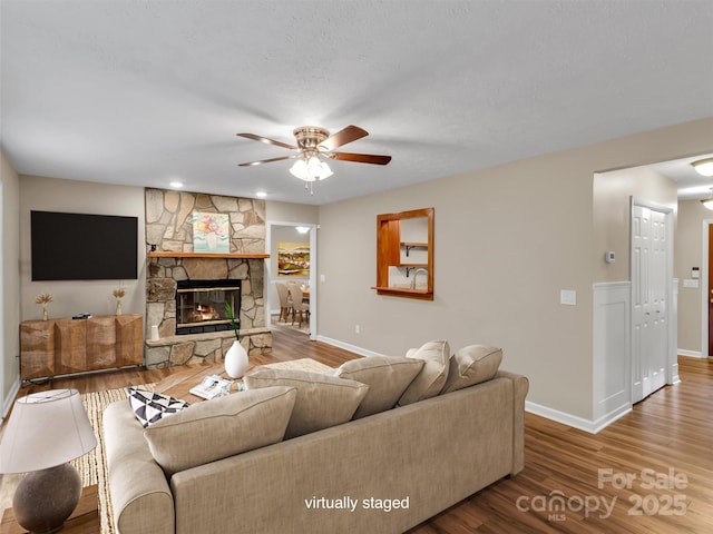 living room with ceiling fan, hardwood / wood-style floors, a textured ceiling, and a fireplace