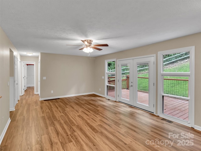 empty room featuring french doors, ceiling fan, light hardwood / wood-style flooring, and a textured ceiling