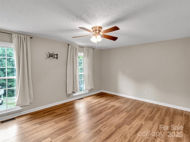 empty room with ceiling fan, light hardwood / wood-style floors, and a textured ceiling