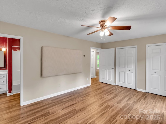 unfurnished bedroom with multiple closets, ceiling fan, a textured ceiling, and light hardwood / wood-style flooring