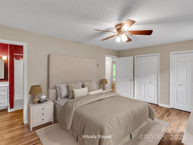 bedroom featuring two closets, a textured ceiling, and light wood-type flooring