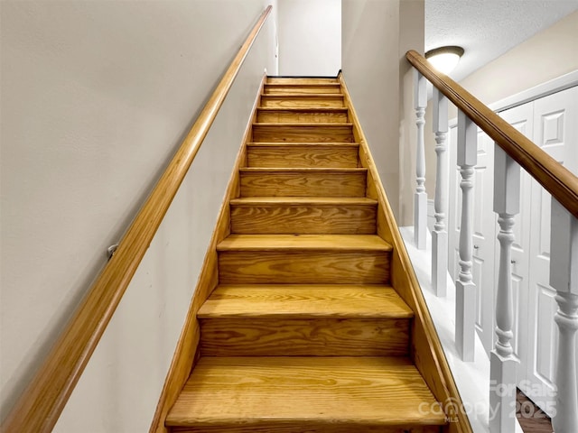 stairs featuring a textured ceiling