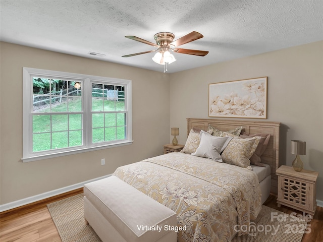 bedroom featuring wood-type flooring, ceiling fan, and a textured ceiling